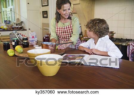 Stock Image - Grandmother and little boy cooking food at kitchen. Fotosearch
