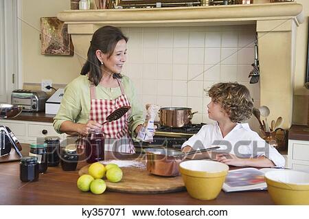 Stock Image - Grandmother and little boy cooking food together at home. Fotosearch