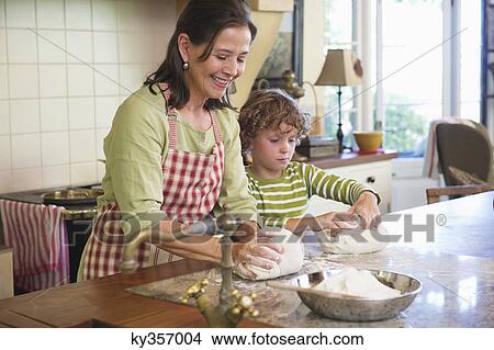 Picture - Grandmother and little boy kneading dough at kitchen. Fotosearch