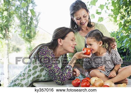 Multi generation family smelling tomatoes View Large Photo Image Stock Photograph - Multi generation family smelling tomatoes. Fotosearch
