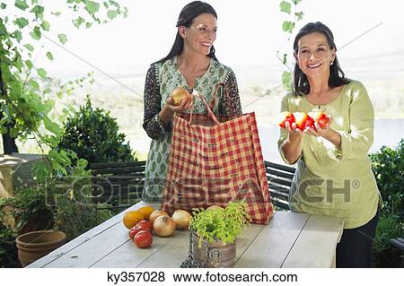 Portrait of a senior woman holding tomatoes with daughter looking at her View Large Photo Image Stock Photo - Portrait of a senior woman holding tomatoes with daughter looking at her. Fotosearch