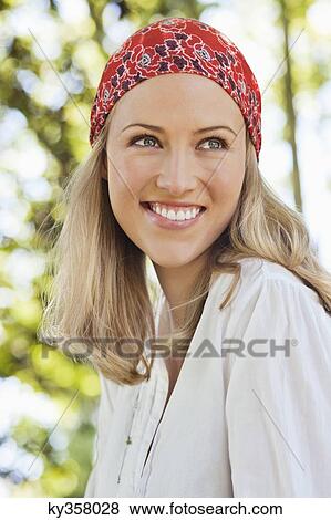 Cheerful young woman wearing bandana and day dreaming View Large Photo Image Stock Photo - Cheerful young woman wearing bandana and day dreaming. Fotosearch