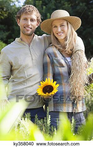Stock Image - Portrait of a couple in scarecrow pose in a field. Fotosearch