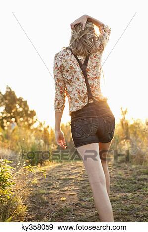 Rear view of a woman walking on a trail View Large Photo Image Stock Photo - Rear view of a woman walking on a trail. Fotosearch