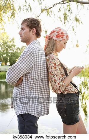 Side profile of a couple standing back to back View Large Photo Image Picture - Side profile of a couple standing back to back. Fotosearch