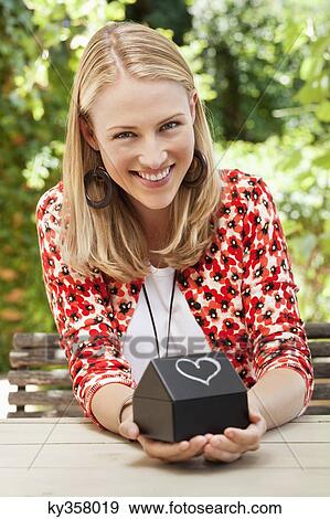 Stock Photo - Woman holding a model home and smiling. Fotosearch