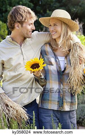 Picture - Young couple in scarecrow pose in a field. Fotosearch