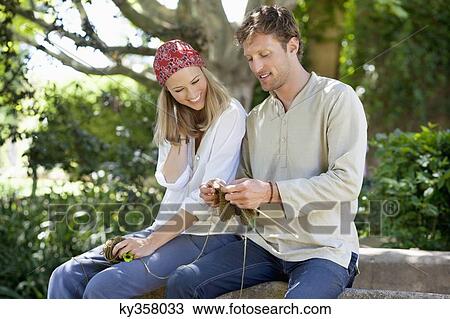 Stock Image - Young couple knitting together and smiling. Fotosearch