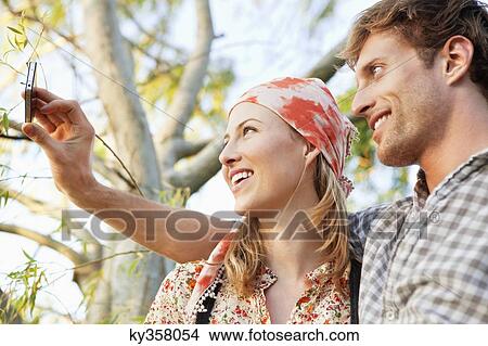 Young couple taking a picture of themselves with a mobile phone View Large Photo Image Picture - Young couple taking a picture of themselves with a mobile phone. Fotosearch