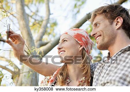 Young couple taking a picture of themselves with a mobile phone View Large Photo Image Stock Photo - Young couple taking a picture of themselves with a mobile phone. Fotosearch