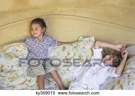 Cute siblings lying on couch at home View Large Photo Image Stock Photography - Cute siblings lying on couch at home. Fotosearch