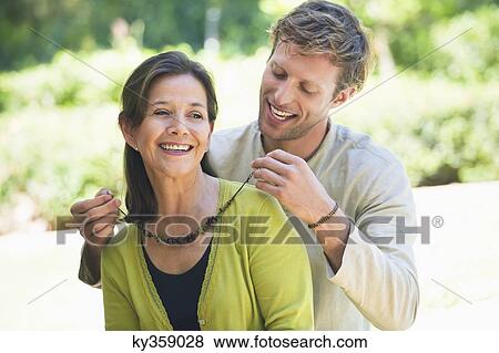 Man fastening mom's necklace outdoors View Large Photo Image Stock Photo - Man fastening mom's necklace outdoors. Fotosearch