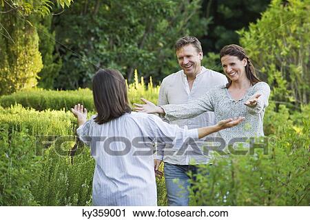Stock Image - Mature couple hugging their mother in a garden. Fotosearch