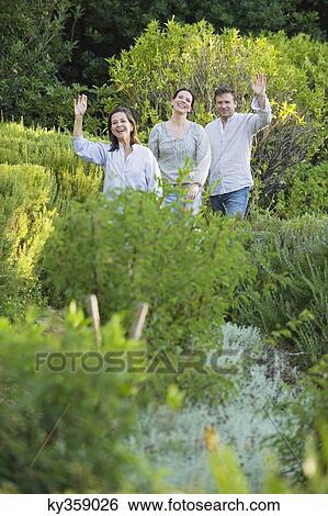 Stock Photograph - Mature couple walking with their mother and waving hand in a garden. Fotosearch