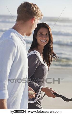 Picture - Couple looking at each other and walking on the beach. Fotosearch