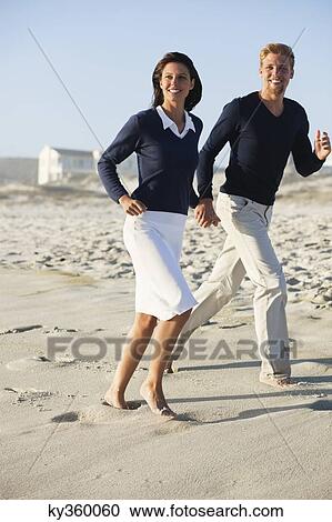 Stock Image - Couple running on the beach. Fotosearch