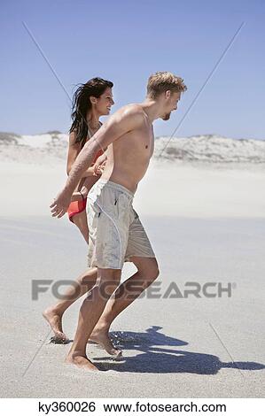 Stock Photograph - Couple walking on the beach. Fotosearch