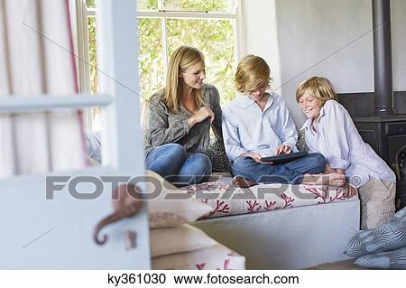Stock Image - Children and their mother using digital tablet at house. Fotosearch