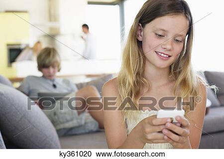 Stock Image - Close-up of a girl using a mobile phone and smiling. Fotosearch