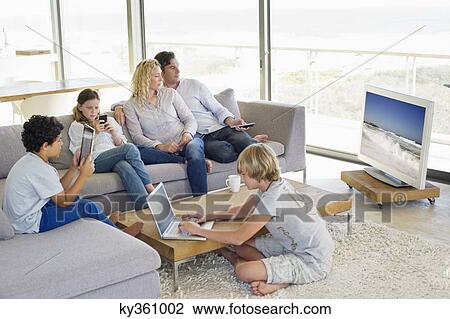 Couple watching television set while their children busy in different activities View Large Photo Image Stock Image - Couple watching television set while their children busy in different activities. Fotosearch