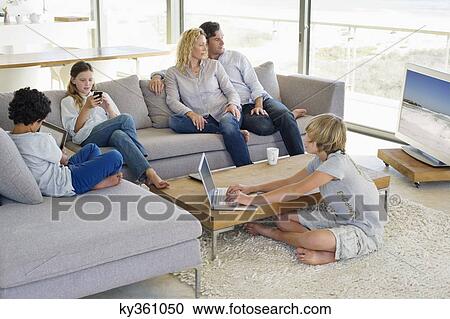 Stock Image - Couple watching television set while their children busy in different activities. Fotosearch