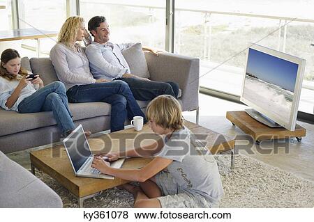 Couple watching television set while their children busy in different activities View Large Photo Image Stock Photo - Couple watching television set while their children busy in different activities. Fotosearch