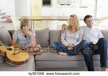 Family sitting on a couch and smiling View Large Photo Image Stock Photograph - Family sitting on a couch and smiling. Fotosearch