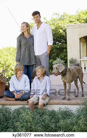 Stock Photo - Family with their dog outside house. Fotosearch