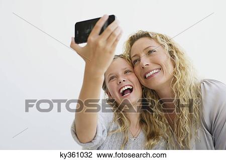 Girl with her mother taking picture of themselves with a mobile phone View Large Photo Image Stock Image - Girl with her mother taking picture of themselves with a mobile phone. Fotosearch