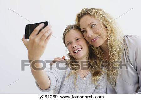 Girl with her mother taking picture of themselves with a mobile phone View Large Photo Image Stock Photo - Girl with her mother taking picture of themselves with a mobile phone. Fotosearch