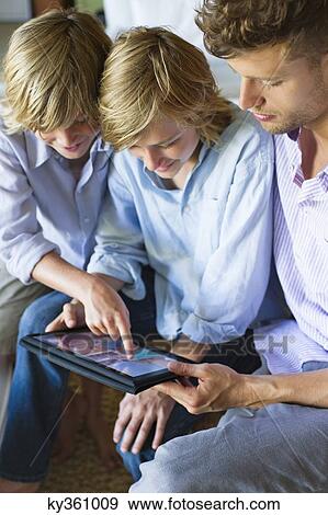 Man and two little boy looking at digital tablet View Large Photo Image Stock Photo - Man and two little boy looking at digital tablet. Fotosearch