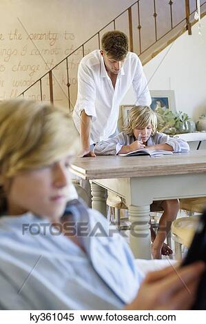 Man teaching little boy with brother using digital tablet in foreground at house View Large Photo Image Stock Photography - Man teaching little boy with brother using digital tablet in foreground at house. Fotosearch