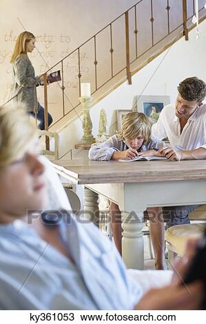 Man teaching little boy with family members busy doing their work View Large Photo Image Stock Image - Man teaching little boy with family members busy doing their work. Fotosearch