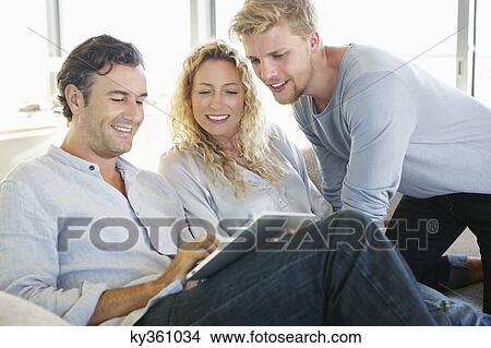 Picture - Mid adult man using a digital tablet and smiling. Fotosearch