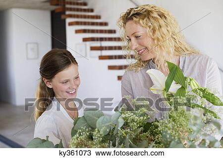 Mid adult woman and her daughter touching leaves and smiling View Large Photo Image Stock Image - Mid adult woman and her daughter touching leaves and smiling. Fotosearch