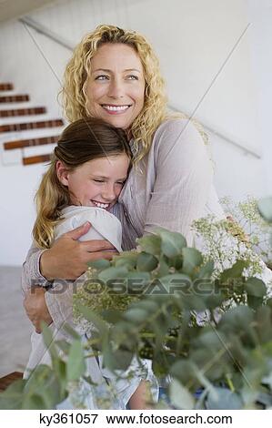 Mid adult woman hugging her daughter and smiling View Large Photo Image Stock Photo - Mid adult woman hugging her daughter and smiling. Fotosearch