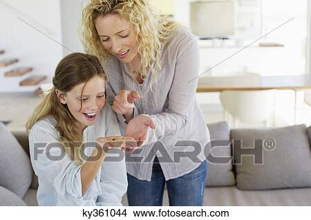 Mid adult woman looking at her daughter's palm and smiling View Large Photo Image Picture - Mid adult woman looking at her daughter's palm and smiling. Fotosearch