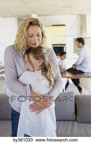 Stock Image - Mother hugging her daughter and smiling. Fotosearch