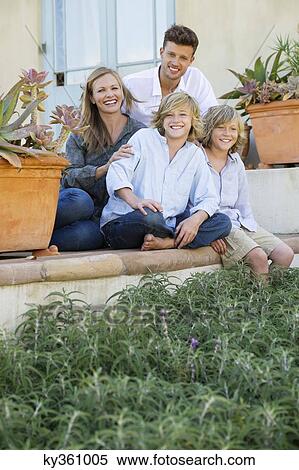 Portrait of a happy family sitting together outside their house View Large Photo Image Stock Photography - Portrait of a happy family sitting together outside their house. Fotosearch