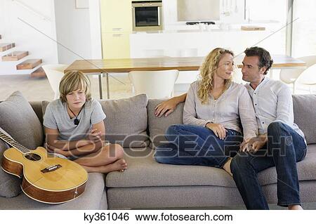 Stock Photograph - Teenage boy sitting with a guitar on a couch. Fotosearch