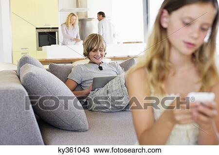 Teenage boy using a digital tablet on a couch View Large Photo Image Stock Image - Teenage boy using a digital tablet on a couch. Fotosearch