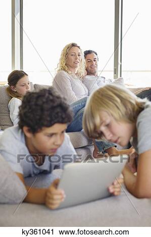 Teenage boy using a digital tablet with his brother and his family in the background View Large Photo Image Stock Image - Teenage boy using a digital tablet with his brother and his family in the background. Fotosearch