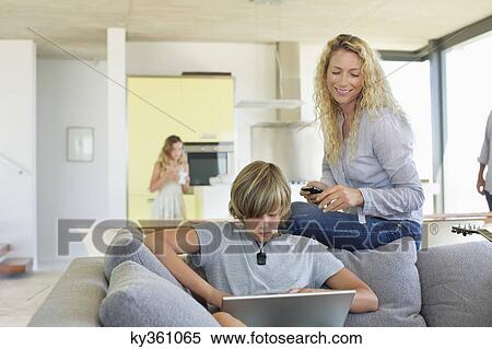 Stock Photography - Teenage boy using a laptop and his mother looking at him. Fotosearch