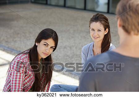 Stock Image - Man standing in front of two women. Fotosearch