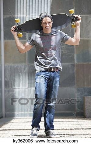 Portrait of man holding skateboard on shoulders View Large Photo Image Stock Photograph - Portrait of man holding skateboard on shoulders. Fotosearch