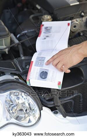 Close-up of a human hand pointing at book while working on broken car engine View Large Photo Image Stock Image - Close-up of a human hand pointing at book while working on broken car engine. Fotosearch
