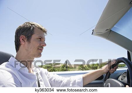 Mid adult man driving a convertible car View Large Photo Image Picture - Mid adult man driving a convertible car. Fotosearch