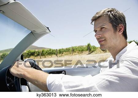 Mid adult man driving a convertible car View Large Photo Image Stock Image - Mid adult man driving a convertible car. Fotosearch