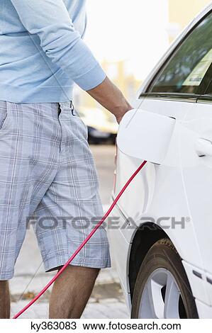 Mid section view of a mid adult man charging the electric car View Large Photo Image Stock Image - Mid section view of a mid adult man charging the electric car. Fotosearch