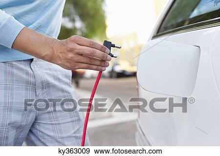 Mid section view of a mid adult man charging the electric car View Large Photo Image Stock Photo - Mid section view of a mid adult man charging the electric car. Fotosearch